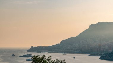 Monte Carlo, Monaco 'da yaz günbatımında şehir manzarası. Güneşin batışı ve akşam sisi. Limandaki büyük yatlar. Kaptan Martin 'den üst görünüm