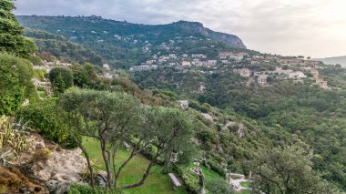 Gündoğumundan sonra Fransız Rivierası 'ndaki Eze köyünün tepesinden ortaçağ evlerinin ve bahçelerinin sabah manzarası. Yeşil ağaçlar ve bulutlu gökyüzü