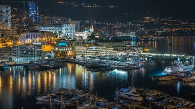 Monte Carlo 'nun Panorama' sı, Monaco köyündeki gözlem güvertesinden geceleri Herkül Limanı 'yla birlikte kumarhaneyle birlikte. Liman manzaralı, aydınlık binalar ve yatlar. Yolda trafik vardı.
