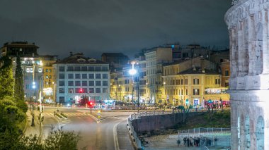 Colosseum yakınlarındaki meydan Roma, İtalya 'da gece saatlerinde aydınlandı. Üst Manzara. Yolda trafik vardı.
