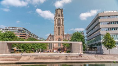 Laurenskerk 'in (Saint Lawrence Kilisesi) Grotekerkplein, Rotterdam' daki hiperlapesi. İnsanlar mavi bulutlu gökyüzünün altında çimlerde dinleniyorlar. Kanal merdivenlerinin yanında saati olan tarihi çan kulesi. Hollanda