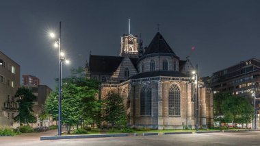 Laurenskerk 'in (Saint Lawrence Kilisesi) geceleyin Rotterdam' da Grotekerkplein 'de yaptığı hiperlapse. Zaman ayarlı tarihi çan kulesiyle aydınlatılmış. Parktaki yeşil ağaçlar. Hollanda