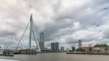 Rotterdam, Hollanda 'daki Maas Nehri' ni kapsayan Erasmus Köprüsü zaman atlaması. Hollanda 'nın en büyük kablo destekli baskülü köprüsü gökdelenleri, rıhtımdaki tekneleri ve dramatik bulutlu gökyüzü arkaplanı