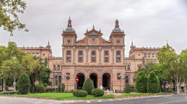 İspanya, Seville 'deki 2. Askeri Bölgenin Kaptanlığı cephesi. Endülüs 'teki Kara Kuvvetleri Karargahı. Trafik, bulutlu gökyüzü ve yeşil ağaçlarla hızlandırılmış zaman aşımı.