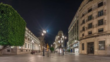Avenida de la Constitucion gece vakti Seville, İspanya 'da aşırı hız. Iconic Adriatica binası akşam parlıyor. Modern sokak lambaları, yayalar ve şehir atmosferine sahip tarihi mimari