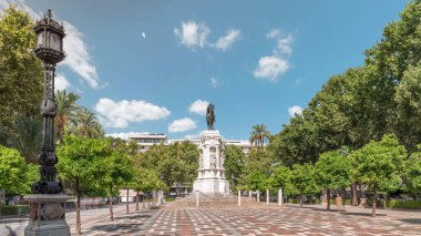 Seville 'deki Plaza Nueva' da, yeşil ağaçlar ve tarihi binalarla çevrili Kral San Fernando 'nun binicilik heykeli yer alıyor. Mavi gökyüzünün altında manzaralı bir şehir alanı