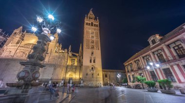 La Giralda ve Seville Katedrali geceleri aşırı hızlanarak altın ışıklarla parıldıyor. Tarihi çan kulesi, gotik detaylar ve aydınlatılmış sokaklar Sevilla, İspanya 'da büyülü bir atmosfer yaratıyor.