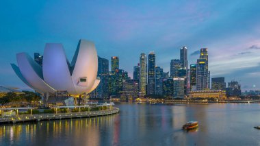 Futuristic architecture flower shape design of the Art Science museum day to night transition timelapse after sunset. Skyscrapers skyline city of Singapore.