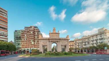 İspanya, Valencia 'da La Porta de la Mar zaman atlaması. Bir zamanlar ortaçağ duvarlarının bir parçası olan bu neoklasik kapı kalabalık bir kavşağın üzerinde duruyor. Gün batımında parlak bir gökyüzünün altında değerli bir şehir simgesi.