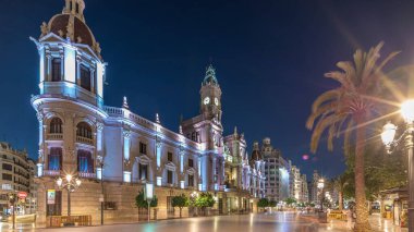 Valencia Belediye Binası (Ajuntament de Valencia) Plaza de Ayuntamiento 'da günden geceye geçiş zamanaşımı üst sürati. Saat kulesi olan tarihi bir bina. İspanya 'nın ana meydanında gezinen insanlar