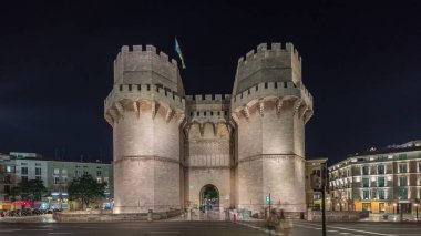 Panorama, Serrans Kuleleri 'nin (Torres de Serranos) Valencia, İspanya' da gece zaman çizelgesini gösteriyor. Şehrin antik duvarlarından gelen büyük bir ortaçağ kapısı. Tarihi bir dönüm noktasının yakınından geçen cadde trafiği