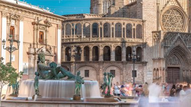 Valencia, İspanya 'daki ikonik Turia Pınarı ile birlikte Plaza de la Virgen' den Timelapse. Neptün heykeli Turia Nehri ve kanallarını temsil eder. Meydanda yürüyen gölgelerle gezen insanlar