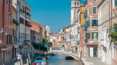 A view of Venice from above timelapse: canal, bridge, boats and an old tower in the background. Blue sky at summer day. People walking around