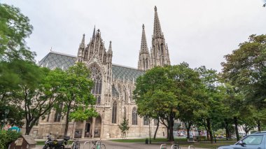 Votivkirche (Votivkirche), Avusturya 'nın başkenti Viyana' daki Halka Caddesi 'nde bulunur. Parkta yeşil ağaçlar ve bulutlu gökyüzü