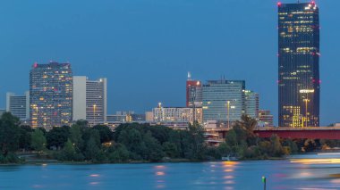 Günbegün modern binalarla dolu güzel şehir manzarası geçiş zamanı, Avusturya 'nın en uzun gökdeleni, gün batımından sonra Viyana' nın Donau bölgesindeki mavi Tuna nehrine yansıdı..