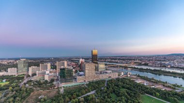 Donau City gökdelenleri, tarihi binalar ve Avusturya 'da gece gündüz nehir kenarındaki gezinti güvertesi ile Viyana üzerinde havadan panoramik bir manzara. Akşam üstü Tuna Kulesi 'nden gün batımından sonra gökyüzü