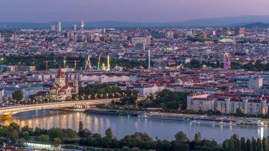 Assisi 'li Aziz Francis Kilisesi ile Viyana üzerinde havadan panoramik bir manzara, Prater, tarihi binalar ve Avusturya' da nehir kenarında bir gezinti alanı. Akşam üstü Tuna Kulesi 'nden gün batımından sonra gökyüzü