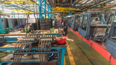 Konveyör montajı, traktörün gövdesini büyük endüstriyel fabrika zaman diliminde sahneleyecek. Kabin montajı, kurulum parçaları özel bir masada.