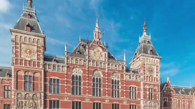 Amsterdam Merkez Tren İstasyonu 'nda tarihi bir girişi olan hiperlapse. Bir sürü yolcu zaman içinde girip çıkıyor. Mavi gökyüzündeki bulutlar. Amsterdam, Hollanda