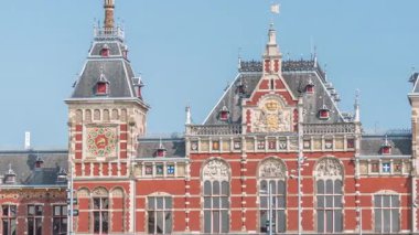 Amsterdam Merkez Tren İstasyonu 'nun zaman çizelgesi yaz günü mavi gökyüzünde bulutlarla kapanıyor. Amsterdam, Hollanda