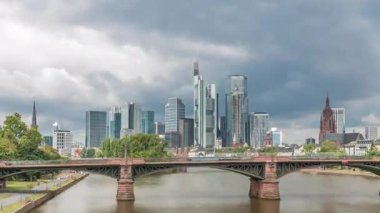 Frankfurt 'un, ana nehir ve Ignatz Bubis Köprüsü' yle olan hiperhızlandırılmış silueti. Gökdelenler ve kilise kuleleri dramatik bulutların altındaki suya yansıyor. Frankfurt, Almanya