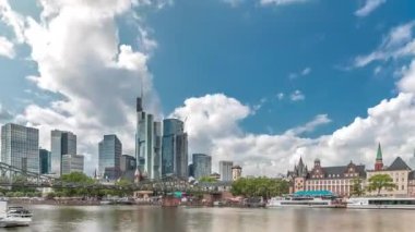 Almanya 'nın Frankfurt kentindeki ana nehir üzerindeki tarihi Eiserner Steg Demir Köprüsü' nün hızlandırılması. Gökdelenler ufuk çizgisi ve tarihi binalar bulutlarla dolu bir zaman dilimi altında suya yansıyor.