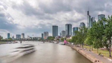 Almanya 'nın Frankfurt kentindeki ana nehir üzerindeki tarihi Eiserner Steg Demir Köprüsü' nün hızlandırılması. Gökdelenler ufuk çizgisi ve kıyı şeridi bulutlarla dolu bir gökyüzünün altında yansıyor.