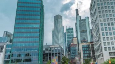 Frankfurts Innenstadt bölgesindeki cam gökdelenlere bakıyorum. Modern mimari gökyüzünde yağmurlu bulutları yansıtır. Yol ayrımında trafik vardı. Almanya.