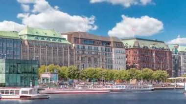 Almanya, Hamburg 'daki Binnenalster zaman ölçümüne bakın. Alster Gölü 'nün iç sularına yansıyan tarihi binalar mavi gökyüzünün altında. Gemili ve rıhtımlı manzaralı şehir manzarası