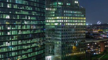 Brüksel 'deki cam cepheli ve parlayan pencereli modern gökdelenlerin ve kulelerin hava gece zaman çizelgesi. Arka planda Eglise Notre-Dame de Laeken 'in yer aldığı aydınlanmış şehir silueti. Belçika