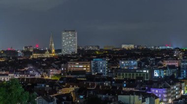 Brüksel üzerinde, Schaerbeek 'teki tren istasyonuna yakın gökdelende hava gecesi panoraması. Yerleşim yerleri, aydınlatılmış Saint-Servais Kilisesi Belçika 'nın başkentindeki kırmızı çatılarla çevrili.