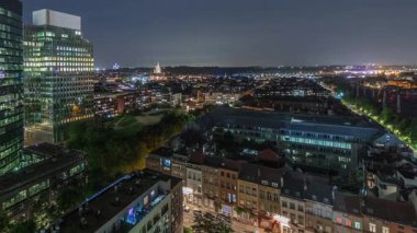 Brüksel kentsel manzarasının, ofis gökdelenleriyle konut alanlarını harmanlayan gece uçuşu. Yeşil park çimenleri, tarihi çatılar ve modern mimari Belçika 'da çeşitli bir şehir manzarası oluşturur