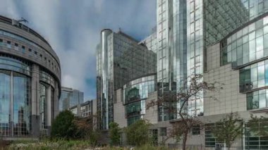 Brüksel 'deki Avrupa Mahallesi' ndeki binalar Avrupa Parlamentosu, Komisyon ve dramatik bulutlu gökyüzü altındaki kurumlarla aynı tarihe denk geliyor. Güneş camdan yansıyor. Leopold Park ön planda çimenlerle