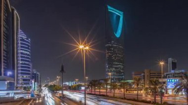 Riyad karayolu trafiğinin yer aldığı panoramik gece zaman çizelgesi, Krallık Kulesi Suudi Arabistan 'ın başkentinin en yüksek gökdeleni ve simgesi. Aydınlatılmış modern binalar canlı sahnenin etrafını sarar.