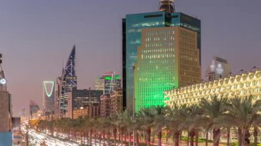 Suudi Arabistan, Riyad 'daki Kral Fahd Yolu' nun hava-gece zaman çizelgesi. Aydınlatılmış Riyad Ulusal Kütüphanesi yakınlarında modern kuleler ve gökdelenlerle çevrili araçlar ve taksilerle dolu.