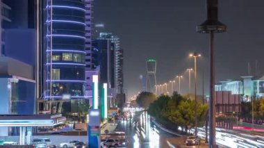 Suudi Arabistan 'ın Riyad kentindeki ikonik bükümlü gökdeleniyle King Fahd Yolu' ndaki yoğun karayolu trafiğinin hava takvimi görüntüsü. Dünyanın en yüksek sekizinci büküm kulesi. Aydınlatılmış sokaklar ve ağaçlar