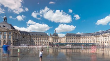 Place de la Bourse ve Miroir d 'eau hiperlapse Bordeaux, Fransa' da, tarihi mimariyi yansıtıyor. Turistler şehir simgesi ve çeşmenin tadını çıkarıyorlar. Trafik ve tramvay zamanı geçiyor..