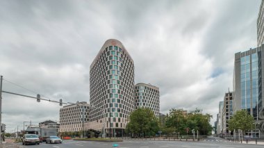 Baudouin Bulvarı, Brüksel, Belçika 'daki iş bölgesi zaman çizelgesinde trafik ve modern ofis binalarını gösteren panorama. Kavşağın yanındaki çağdaş kuleler bulutlu bir gökyüzünün altına park ederler.