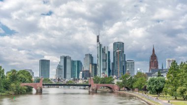 Frankfurt 'un gökdelenlerinin yükselişi Saint Bartholomew İmparatorluk Katedrali' nin çan kulesinin ana nehir üzerindeki tarihi taş köprü Alte Brucke 'ye bakışıyla gerçekleşiyor. Frankfurt, Almanya