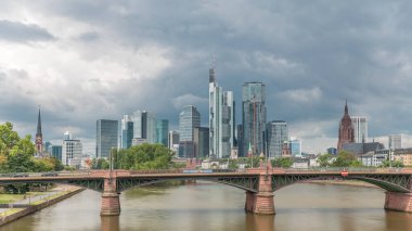 Frankfurt 'un, ana nehir ve Ignatz Bubis Köprüsü' yle olan hiperhızlandırılmış silueti. Gökdelenler ve kilise kuleleri dramatik bulutların altındaki suya yansıyor. Frankfurt, Almanya