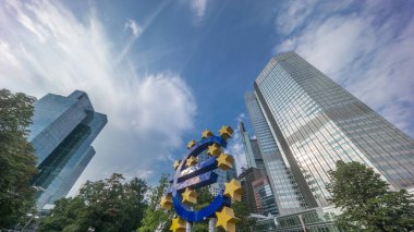 Avrupa Merkez Bankası 'nın eski genel merkezi yakınlarındaki Frankfurt şehir merkezinde Avrupa para birimi tabelasının zaman aşımına uğraması. Güneş ışığı bulutlu bir gökyüzünde gökdelenlerden yansıyor. Almanya