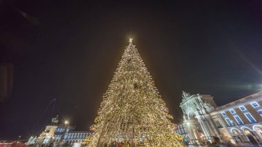 Lizbon 'daki ticaret meydanı, Noel' in aşırı hızıyla aydınlandı. Yükselen bir ağaç ve geceleri kutlayan kalabalıkla. Dekorasyon ve tarihi mimarinin yer aldığı şenlikli atmosferin zamanlaması