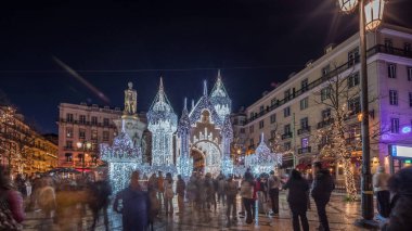 Lizbon, Portekiz 'deki Luis de Camoes meydanında aydınlatılmış şatoyla Noel süslemelerinin gece süreleri. İnsanlar şenlikli ışıkların ve tarihi mimarinin etrafında dolanıyor. Ön görünüm
