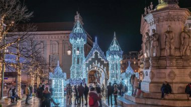 Lizbon, Portekiz 'deki Luis de Camoes meydanında aydınlatılmış şatoyla Noel süslemelerinin gece süreleri. İnsanlar festival ışıkları ve tarihi mimari etrafında yürüyorlar..