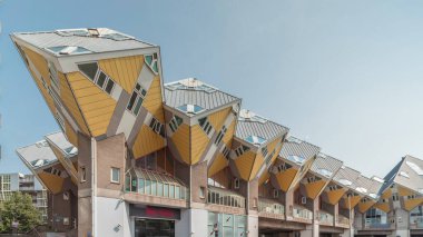 Rotterdam 'daki Küp Evi' nin (Kubuswoningen) hiperlapesi. Eşsiz sarı küp şekilli evler şehrin zaman dilimi içinde yenilikçi mimari sergiliyor. Mavi gökyüzü ve şehir canlılığı. Hollanda