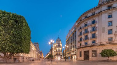 Avenida de la Constitucion, Seville, İspanya 'da günden geceye zaman dilimi. Modern sokak lambaları, yayalar ve kentsel atmosferi olan tarihi mimari. Iconic Adriatica binası gün batımından sonra parlıyor.