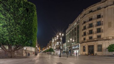 Avenida de la Constitucion gece vakti Seville, İspanya 'da aşırı hız. Iconic Adriatica binası akşam parlıyor. Modern sokak lambaları, yayalar ve şehir atmosferine sahip tarihi mimari