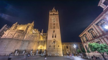 La Giralda ve Seville Katedrali geceleri aşırı hızlanarak altın ışıklarla parıldıyor. Tarihi çan kulesi, gotik detaylar ve aydınlatılmış sokaklar Sevilla, İspanya 'da büyülü bir atmosfer yaratıyor.