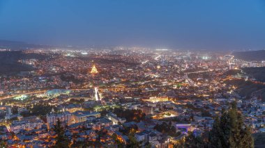 Alacakaranlıkta Tiflis şehri, Gürcistan 'dan gece geçiş zamanı. Şehir merkezinin ve Tiflis 'teki Kura Nehri' nin üst manzarası. Gün batımından sonra Gürcistan başkentinin havadan görünüşü
