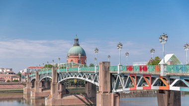 Garonne Nehri 'nin üzerindeki Saint Pierre Köprüsü' nde su ve La Grave Hastanesi 'nin arka planında bulutlu mavi bir gökyüzünün altında yansımaları var. Klasik sokak lambaları cazibe katar. Toulouse, Fransa